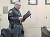 Officer reading from a document in a meeting room.