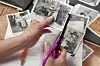 Hands cutting photographs with scissors on a table.