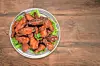 Glazed chicken wings on a plate with lettuce.