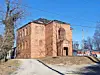 Historic brick building with boarded windows under a blue sky.
