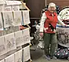 Elderly woman next to a craft display at a fair.