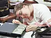 Woman repairing a laptop at a workshop table.