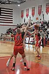 Players in red and black uniforms compete for a basketball.