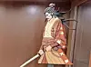 Stylized samurai figure with a sword in a wooden setting.