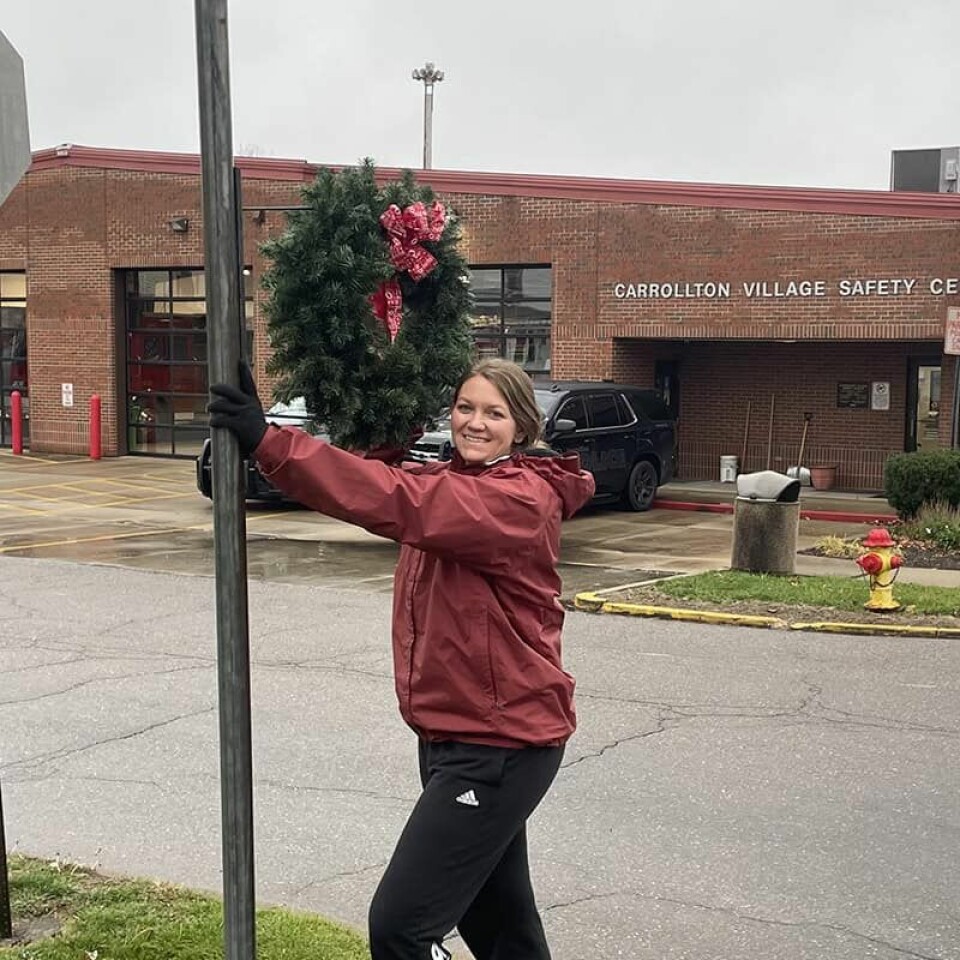 Submitted PhotoSuburban Garden Club members are preparing the village for the upcoming holiday season by placing wreaths on street signs. The Carrollton Business Women decorated the downtown area for events, which kick off the weekend of Nov. 30. In the above photo, Kristen Buchanan fastens a wreath on a street sign.