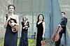 String quartet in black dresses and suits in an urban setting.