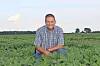 Farmer kneeling in a green soybean field.