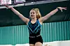 Young gymnast on balance beam with arms outstretched.