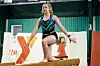 Young gymnast on balance beam in a gym setting.