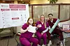 Three healthcare professionals pose with wellness materials at an event.