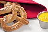 Soft pretzels with mustard on a red napkin.