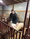 Young farmer with pig in barn setting.