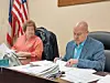 Two officials at a desk reviewing documents.