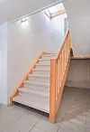 Interior staircase with wooden railing and white walls.