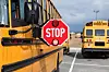 School bus stop sign with buses in the background.