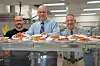 School staff serving pizza in a cafeteria.