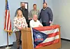 Group of community leaders posing in front of a flag.