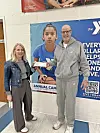 Donation presentation at YMCA with two individuals and a promotional banner.