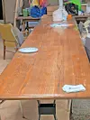 Long wooden table with plates and papers in a communal space.