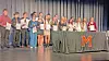 Students holding certificates on stage at an award ceremony.