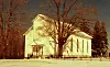 Historic church surrounded by snow and trees.