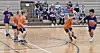 Children playing basketball in a gym.