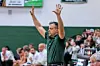 Coach with raised hands on basketball sidelines.