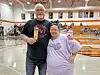 A man and a woman holding an award in a gym.