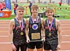Three athletes holding a trophy and medals at a track event.