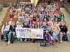 Students holding a banner for exploring STEM day in an auditorium.