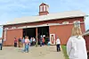 Visitors near a red barn with a clock tower.