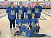 Youth bowling team in blue shirts posing together.