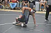 Two wrestlers grappling on a mat in a gym.
