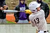 Baseball player swinging a bat with spectators behind.