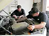 Two mechanics working on a vehicle's engine.