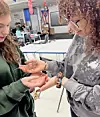 Two students holding a gecko in a classroom.
