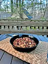 Cast iron skillet with food on a table outdoors.