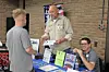 Two men interact at an informational booth in a community setting.