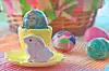Ceramic bunny with decorated Easter eggs on a colorful table.