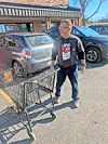 Man with a shopping cart in a parking lot.