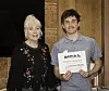 Student holding a certificate with a smiling woman beside him.