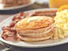 Breakfast plate with pancakes, eggs, bacon, and sausage.