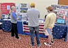 Three people viewing a DAR exhibit with an American flag.
