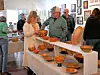 People examining wooden bowls at an art exhibition.