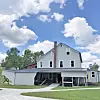 Renovated building with a metal roof and green lawn under a blue sky.