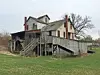 Weathered historic building with stairs and grassy area.