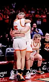 Two basketball players embrace in celebration on the court.