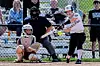 Softball player swings at a pitch with catcher and umpire in view.