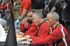 Three people in red shirts working at a conference table.