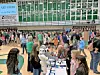 Crowd at an art show in a gymnasium with various displays.